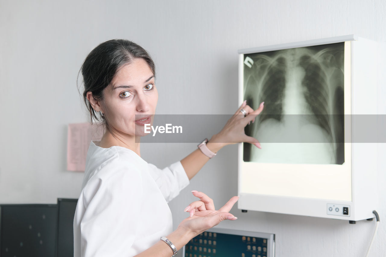 Woman radiologist pointing to the screen with x-ray image of lungs and talking or discussing case