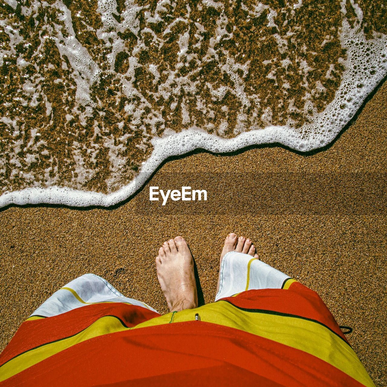 Low section of man standing on shore at beach