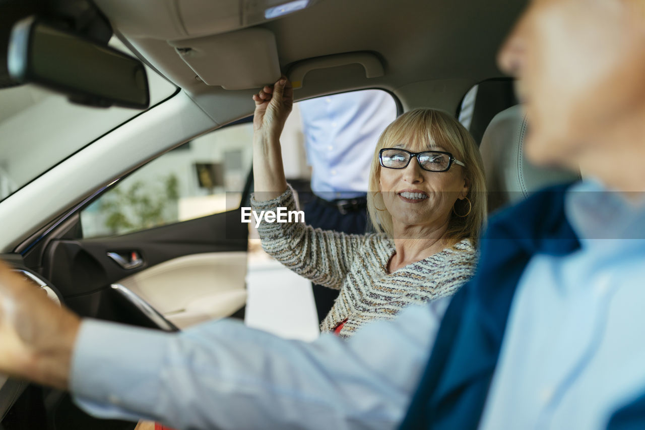 Senior couple trying out car in car dealership