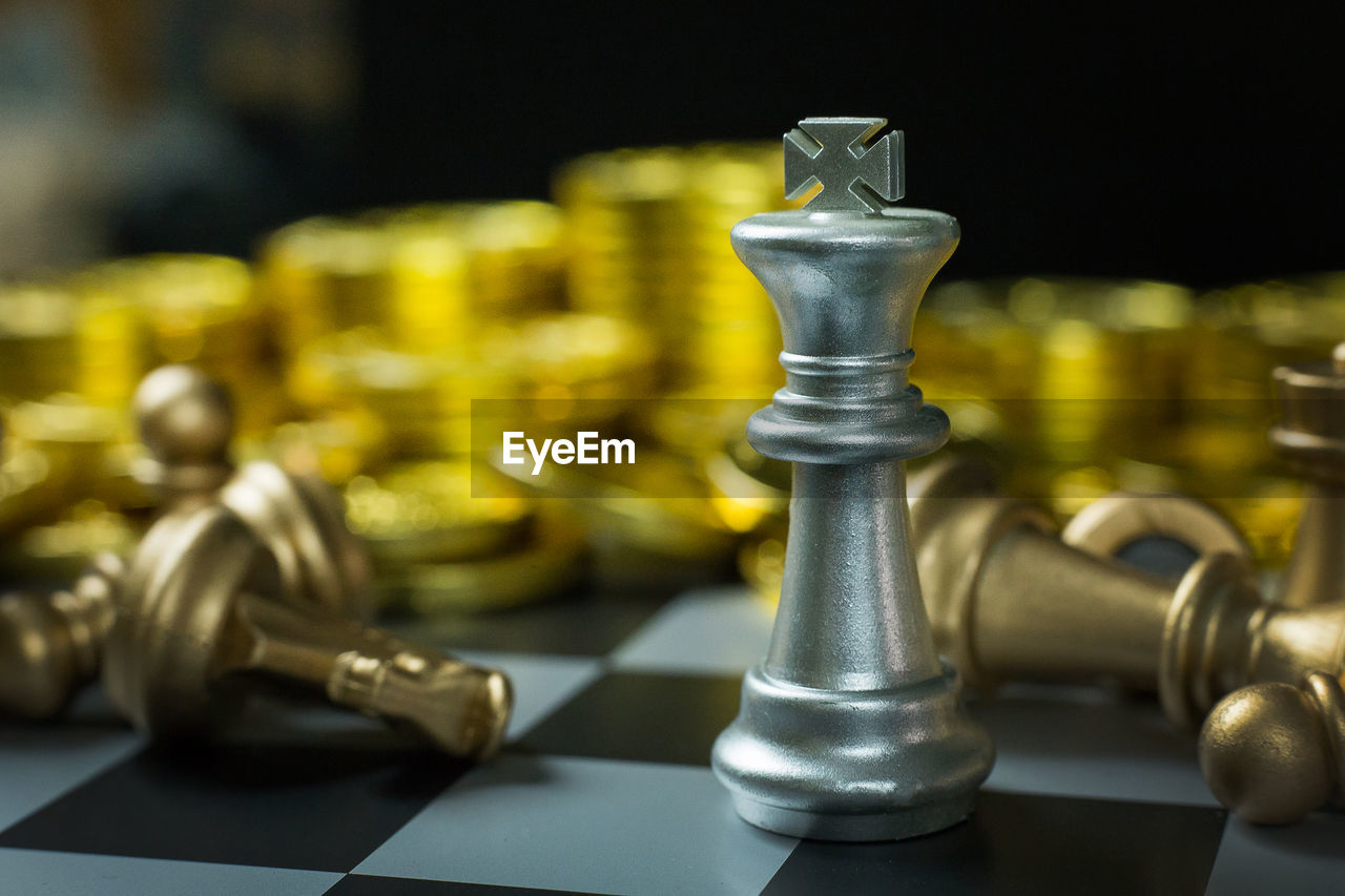 Close-up of chess pieces and coins on board