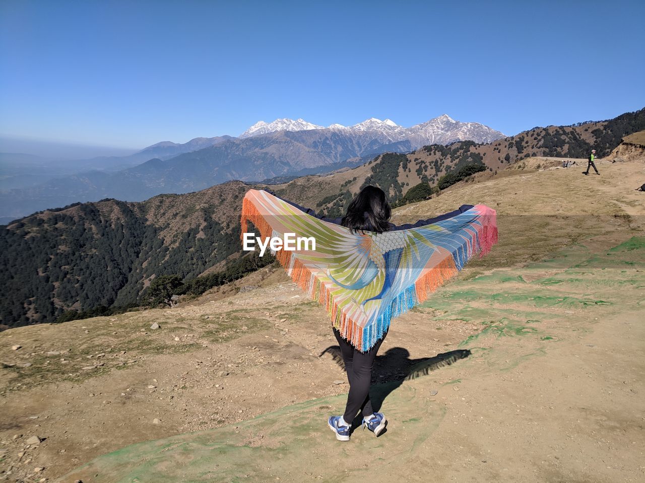 Rear view of woman standing with sarong at mountain peak looking at sky