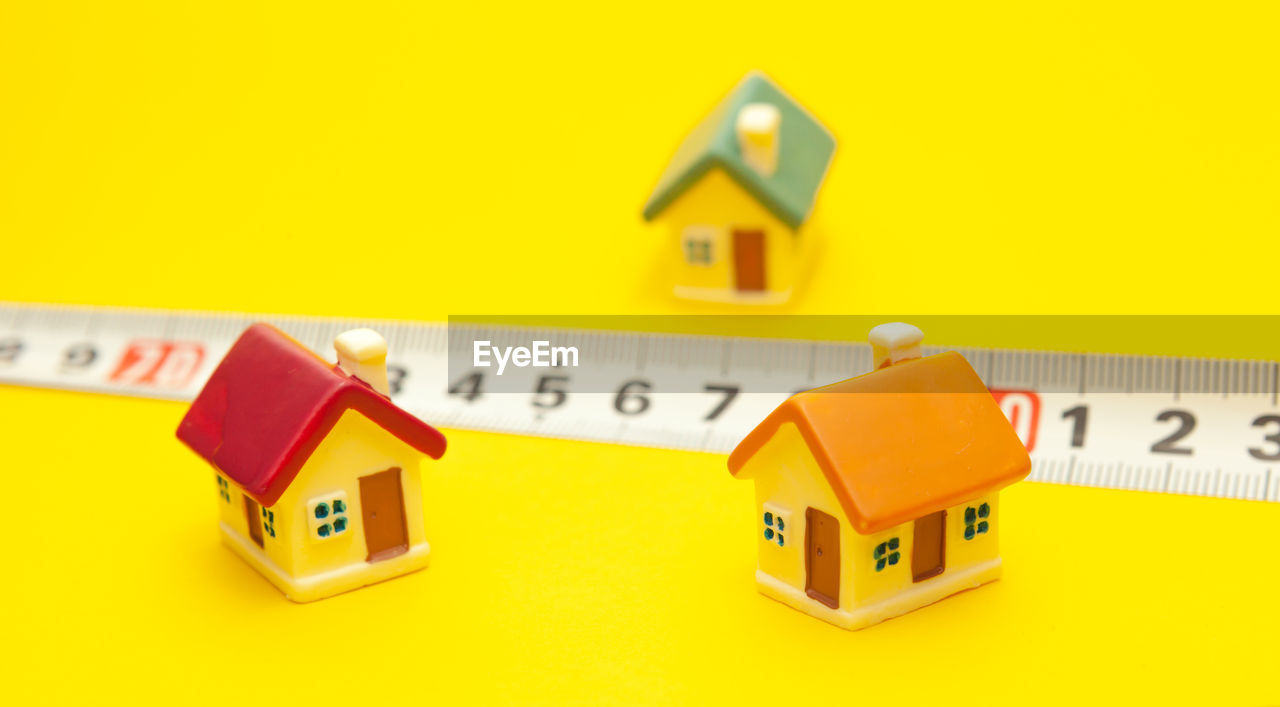 CLOSE-UP OF TOY CAR AGAINST YELLOW WALL AND HOUSE