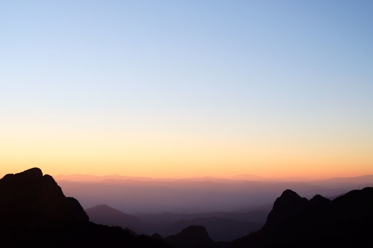 SCENIC VIEW OF SILHOUETTE MOUNTAINS AGAINST ORANGE SKY