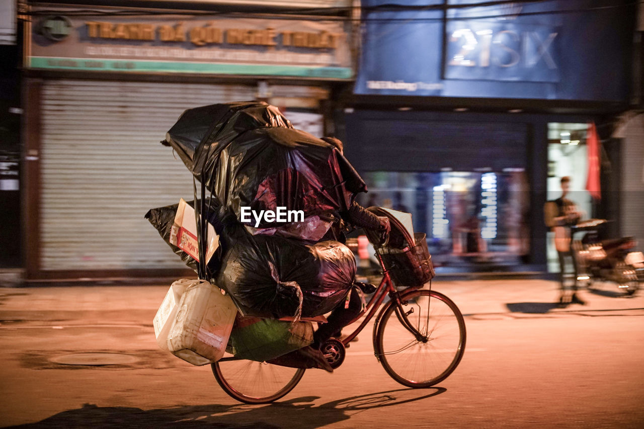 Man with sacks riding bicycle on road at night