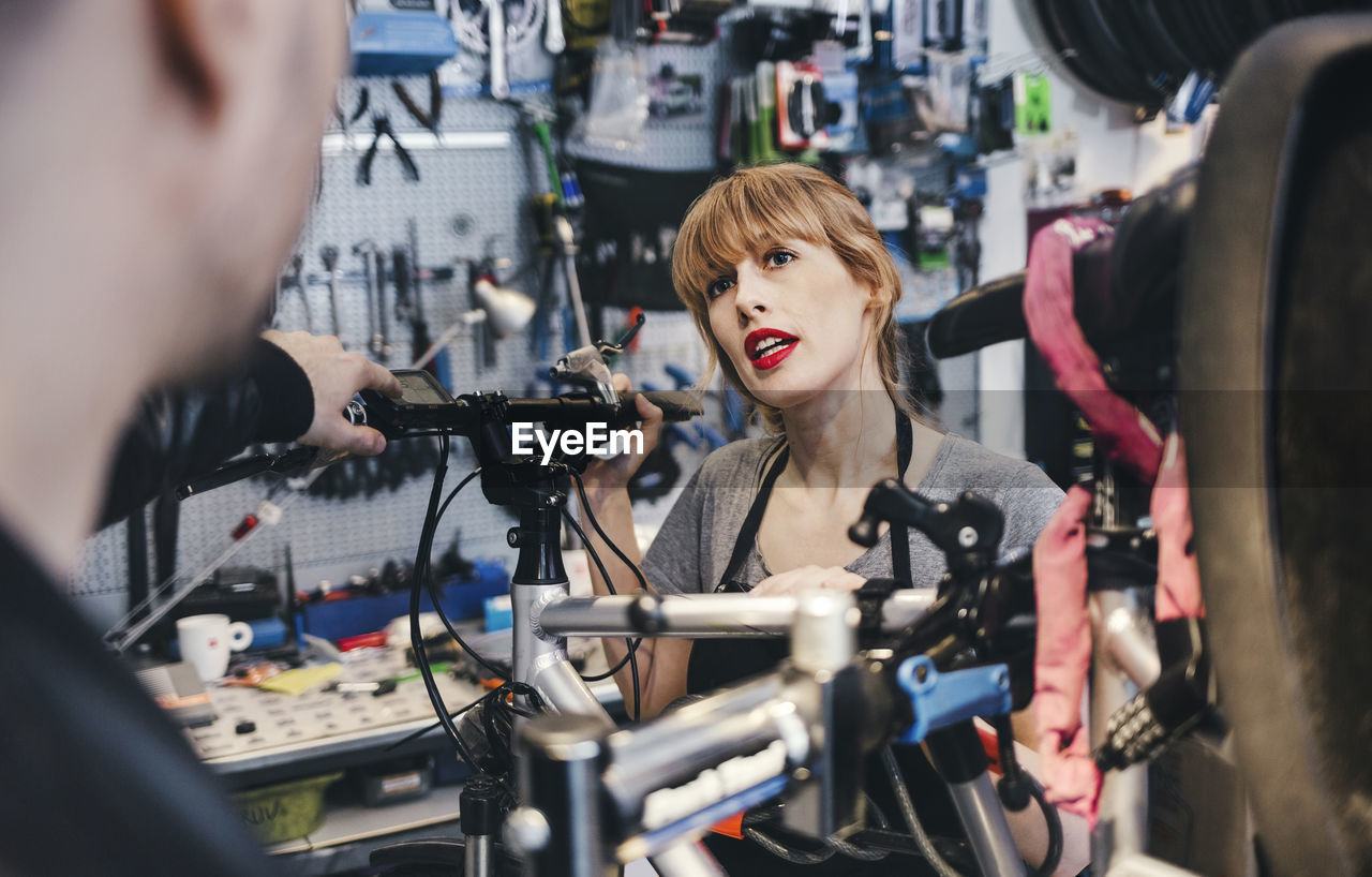 Female mechanic talking to customer in bicycle repair shop