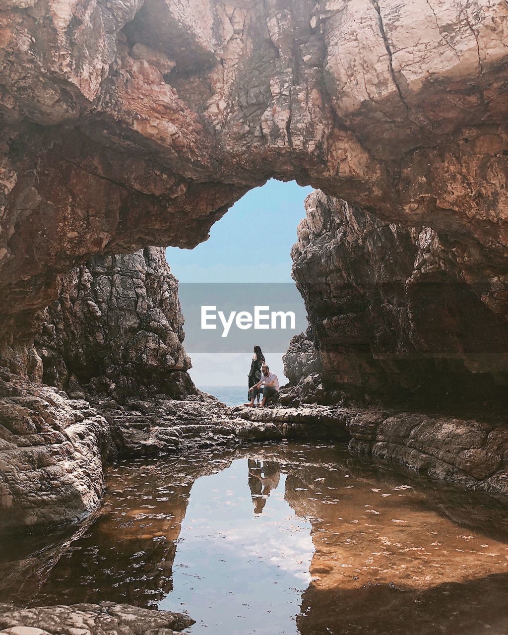 Couple standing on rock formation in water