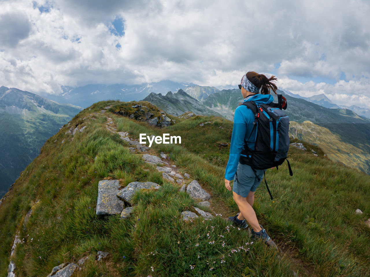 Rear view of woman hiking on rocky mountain peak against sky