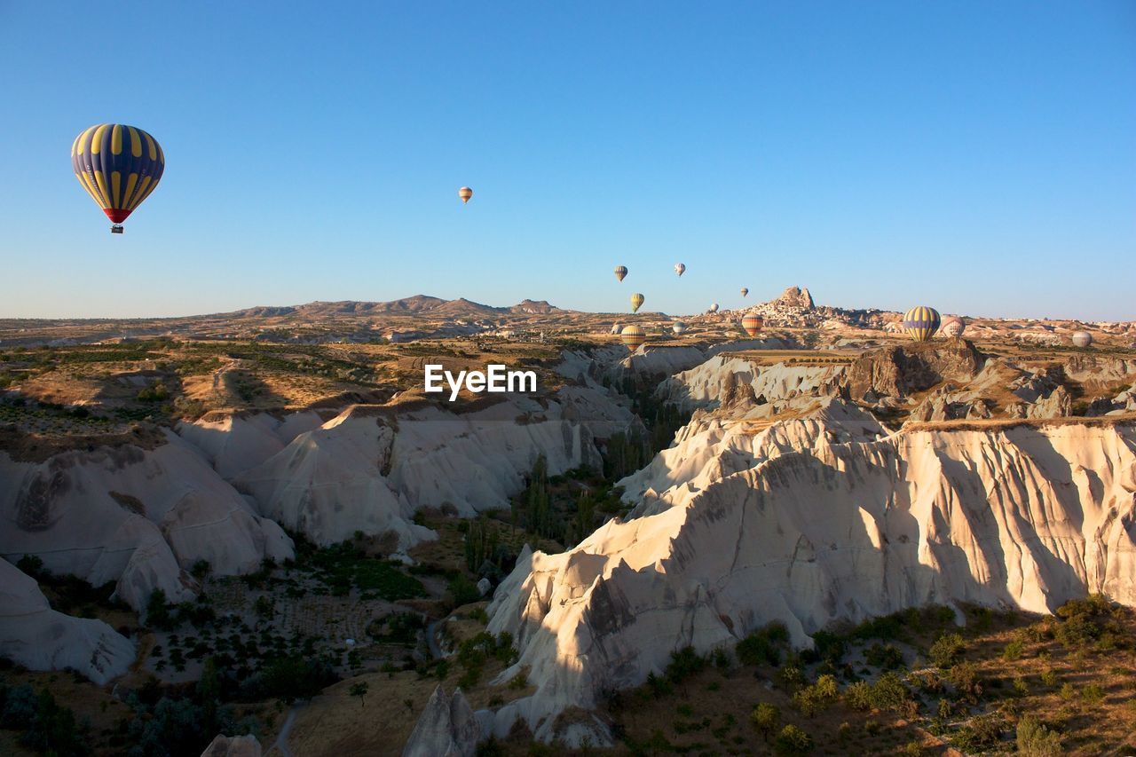 Scenic view of hot air balloons flying over rocky landscape