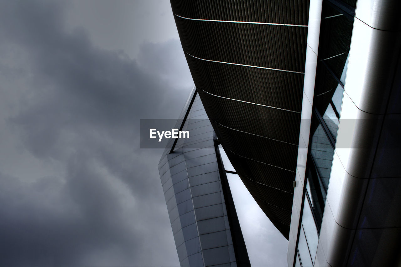 LOW ANGLE VIEW OF MODERN BUILDINGS AGAINST CLOUDY SKY