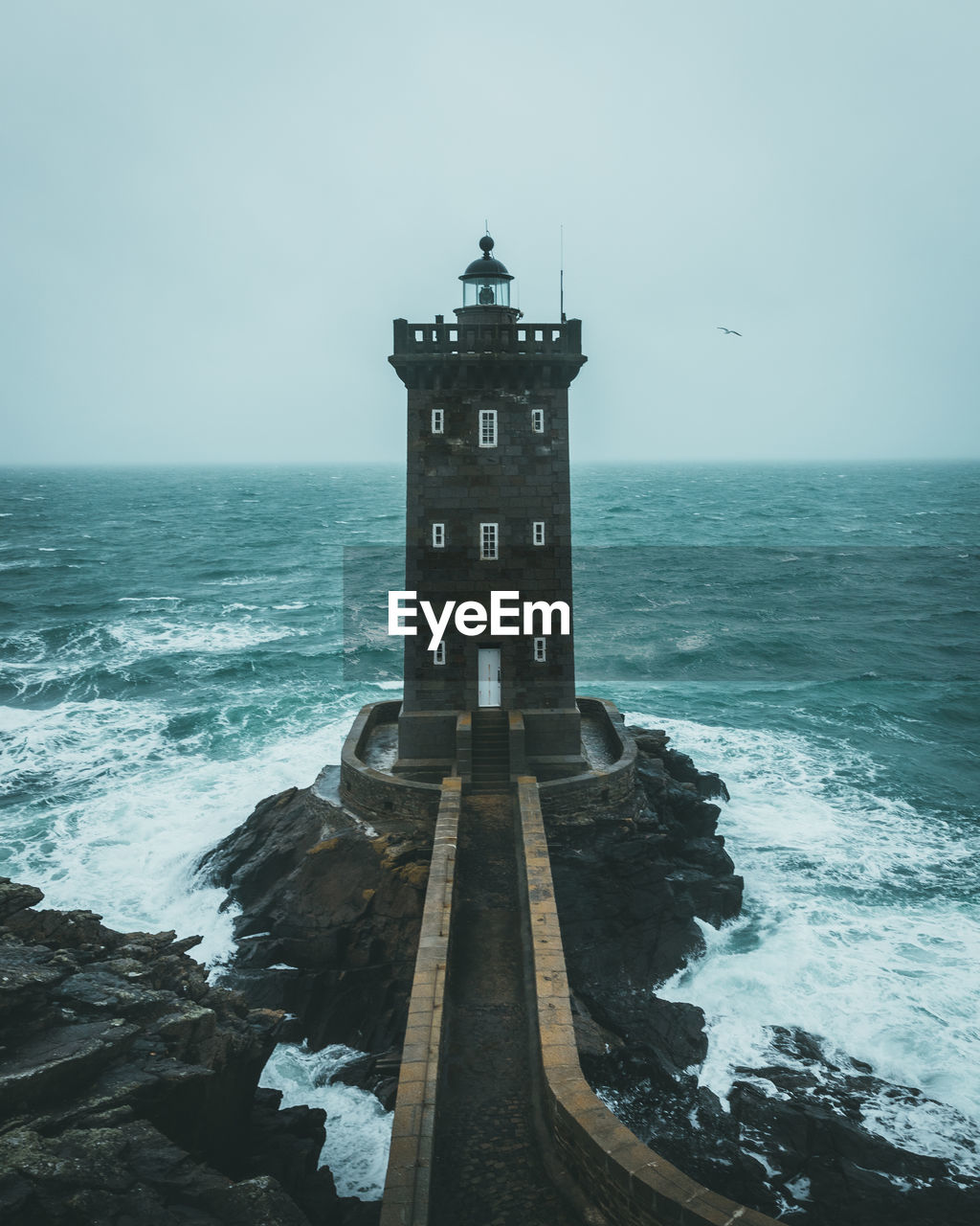 Lighthouse by sea against sky