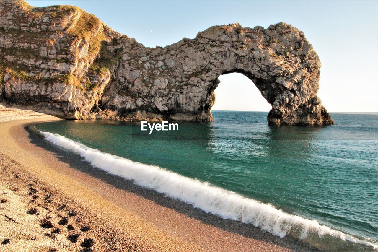 Rock formations on beach against sky