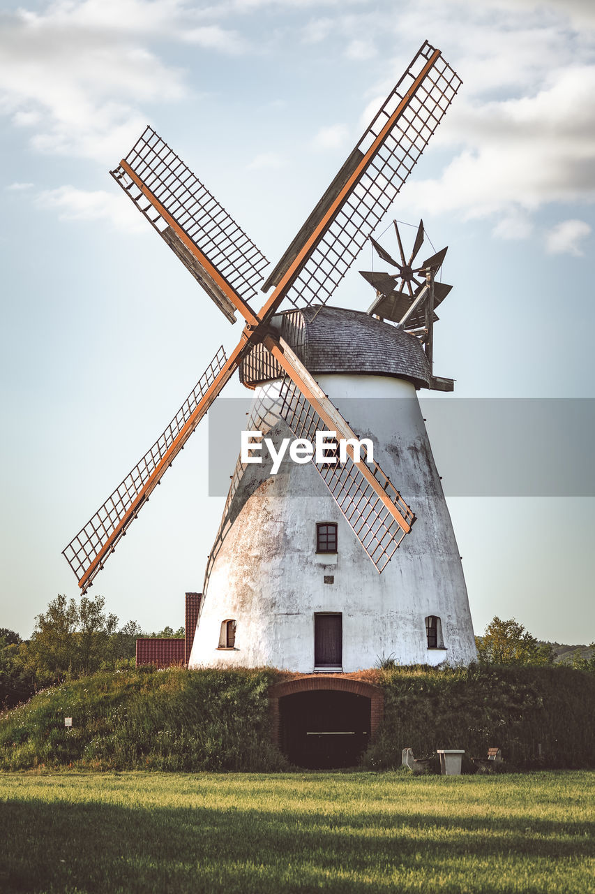 Traditional windmill on field against sky