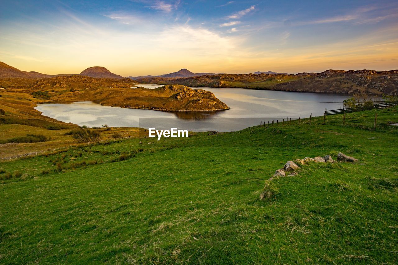 Scenic view of lake and mountains against sky during sunset