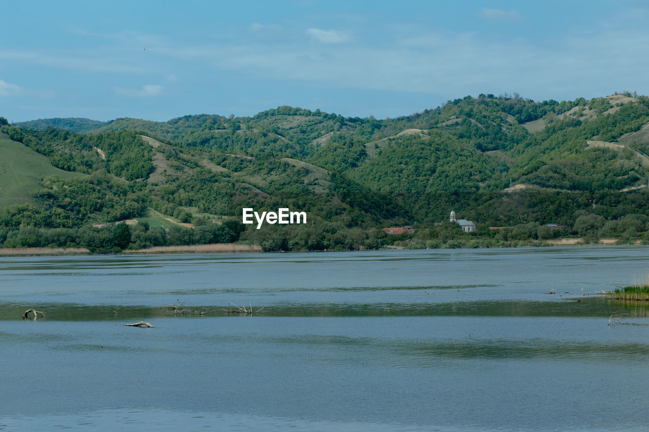 Scenic view of lake by trees against sky