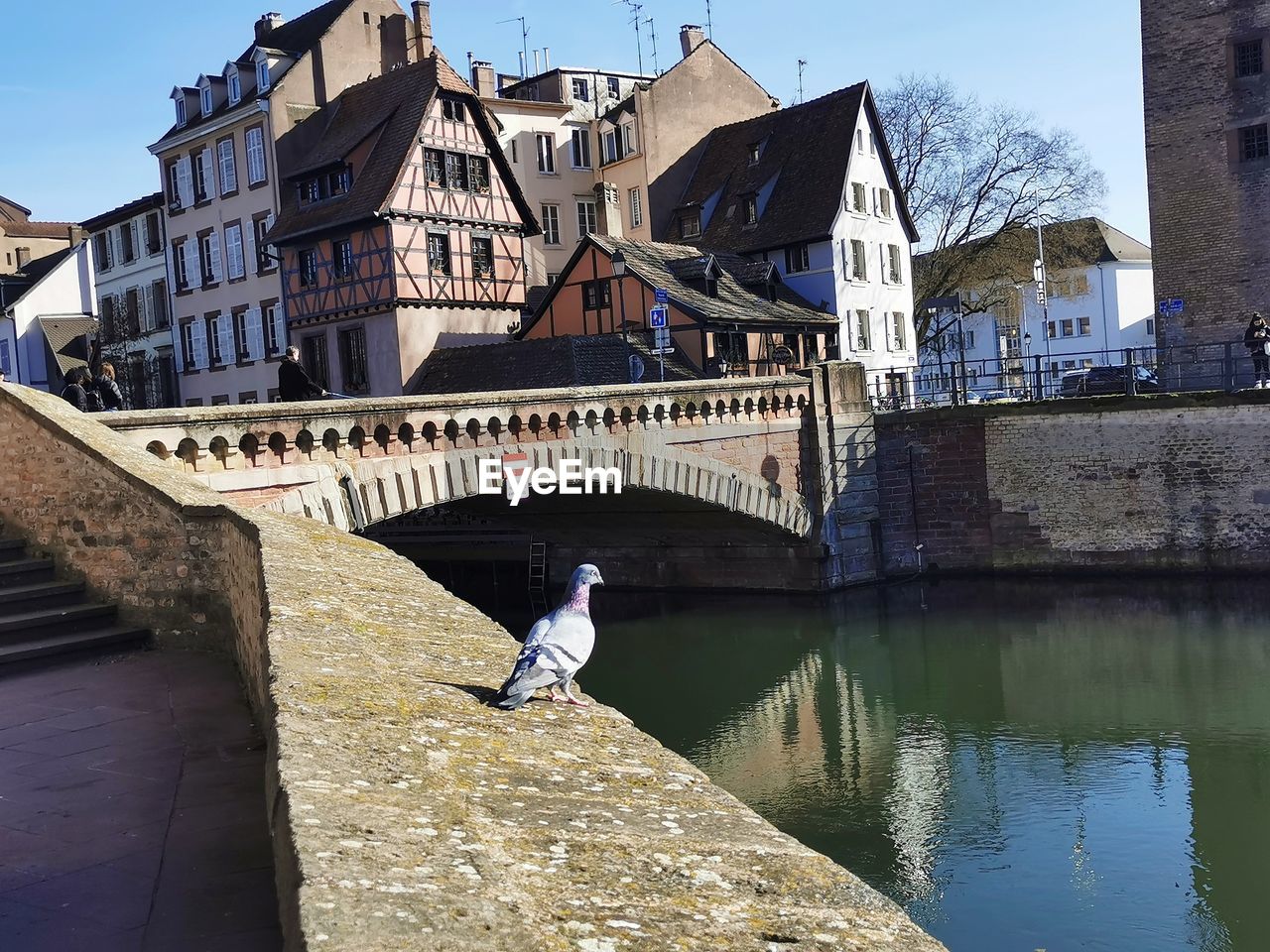 architecture, built structure, water, waterway, building exterior, tourism, reflection, nature, canal, city, town, bridge, sky, travel destinations, building, day, one person, full length, history, outdoors, travel, adult, the past, sunlight, sunny, lifestyles, clear sky, landmark, château, moat, transportation