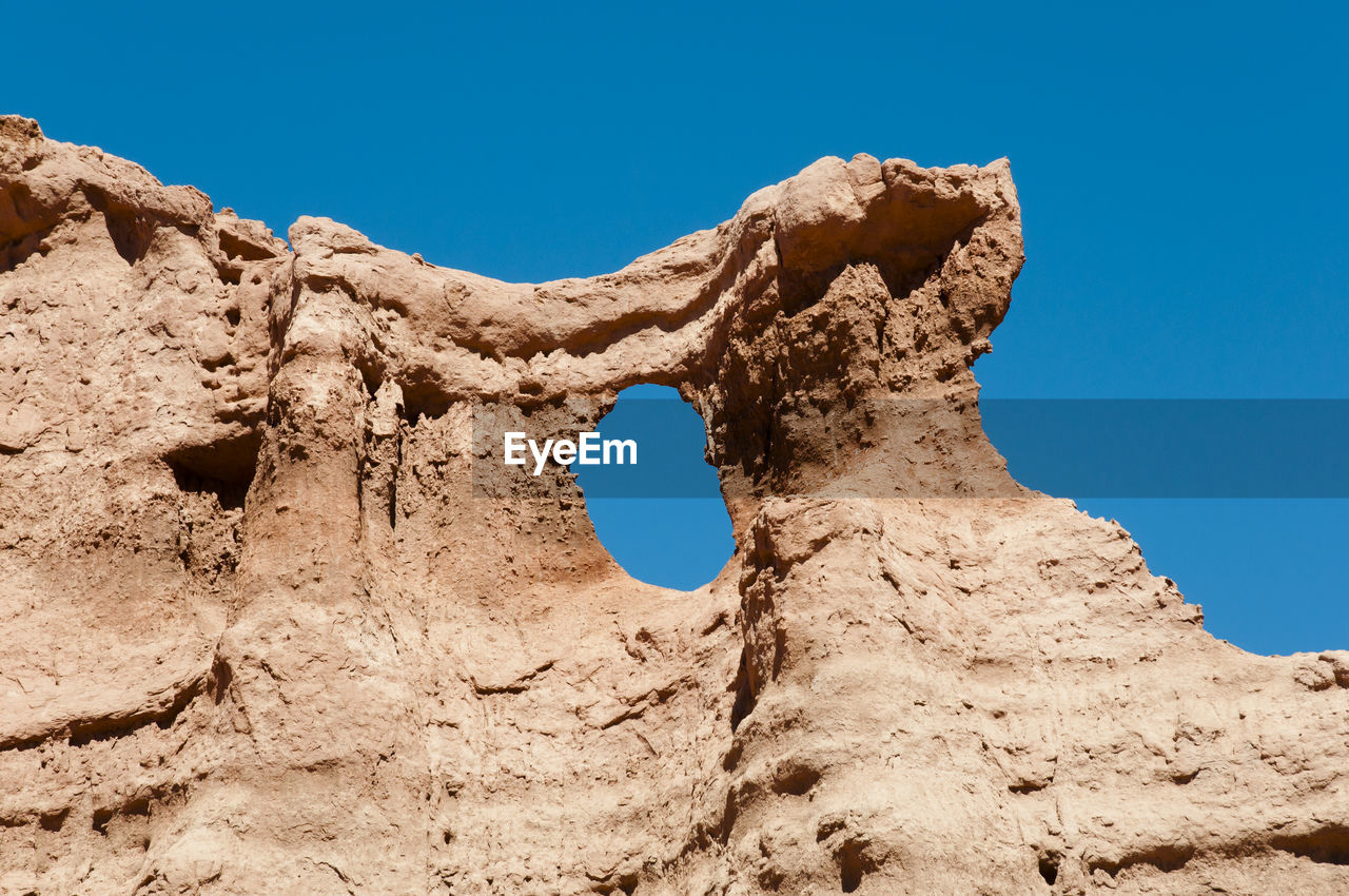 Low angle view of rock formation against clear blue sky