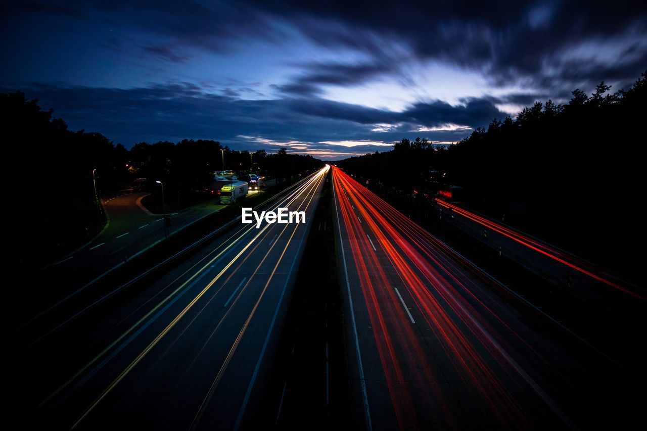 Light trails on road against sky at night