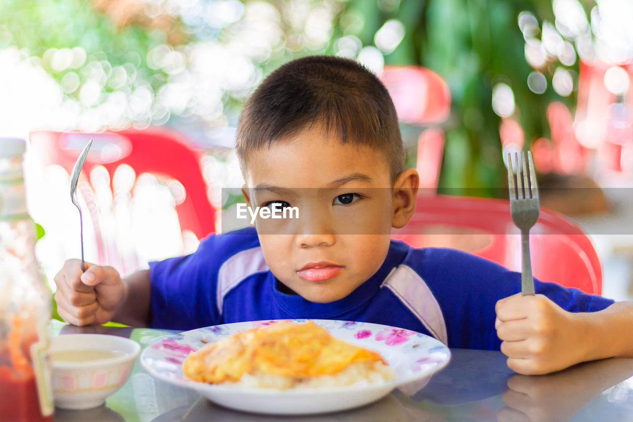 Portrait of cute boy eating food while sitting outdoors
