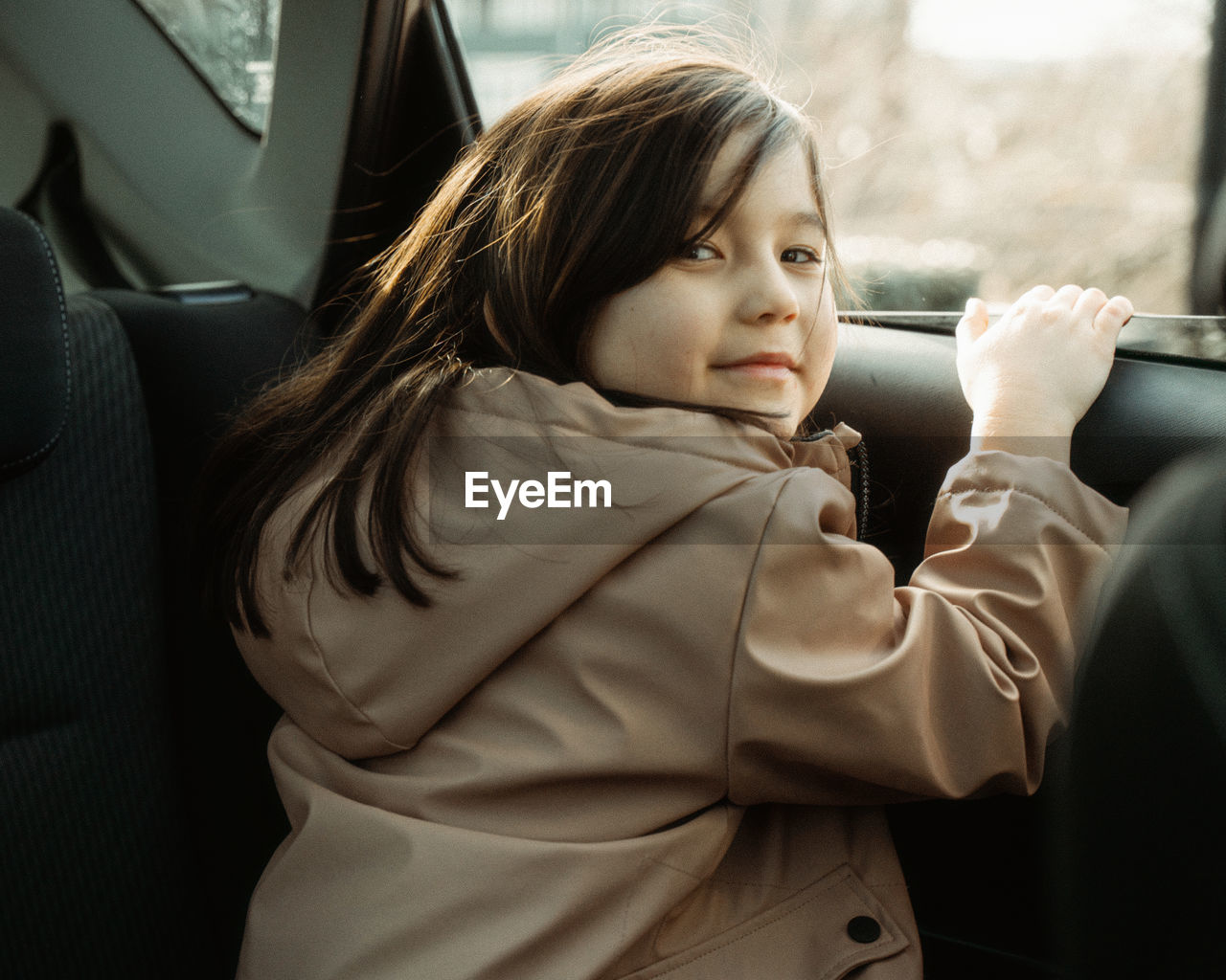 Portrait of young girl sitting in car and looking at camera