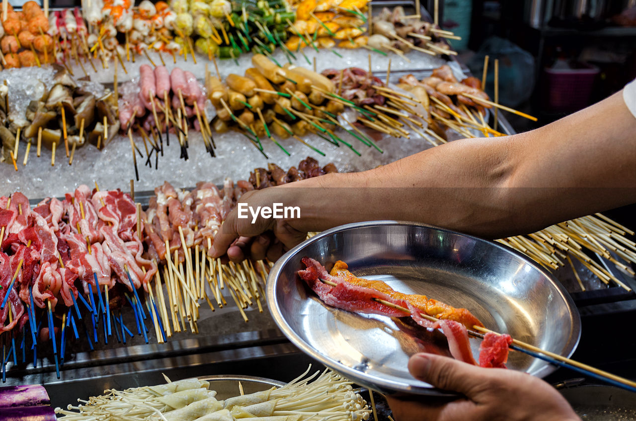 Counter with chinese street food,  buyer  with food on sticks. malaysia, kuala lumpur, jalan alor.