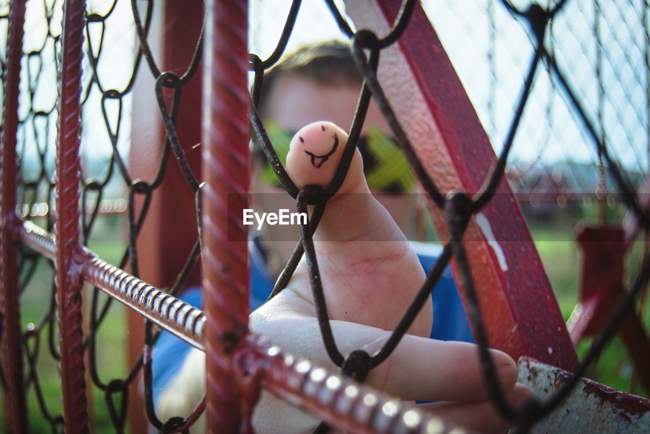 Cropped hand of man on chainlink fence