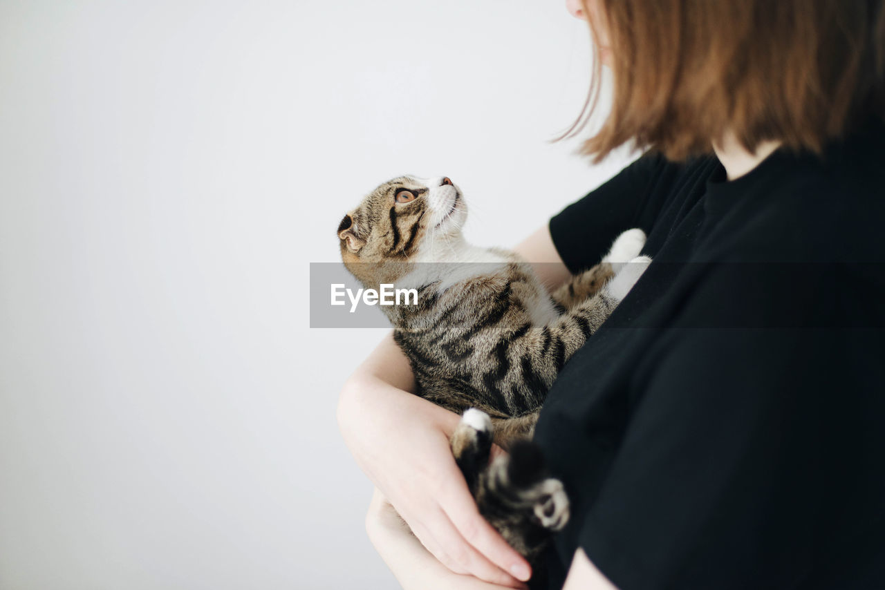 Midsection of woman with cat against white background