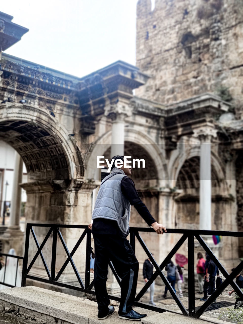 architecture, built structure, building exterior, one person, full length, city, men, adult, street, urban area, rear view, tourism, building, travel destinations, day, history, road, the past, arch, clothing, person, bridge, travel, nature, standing, city life, lifestyles, railing, casual clothing, outdoors, footwear, leisure activity, transportation, sky
