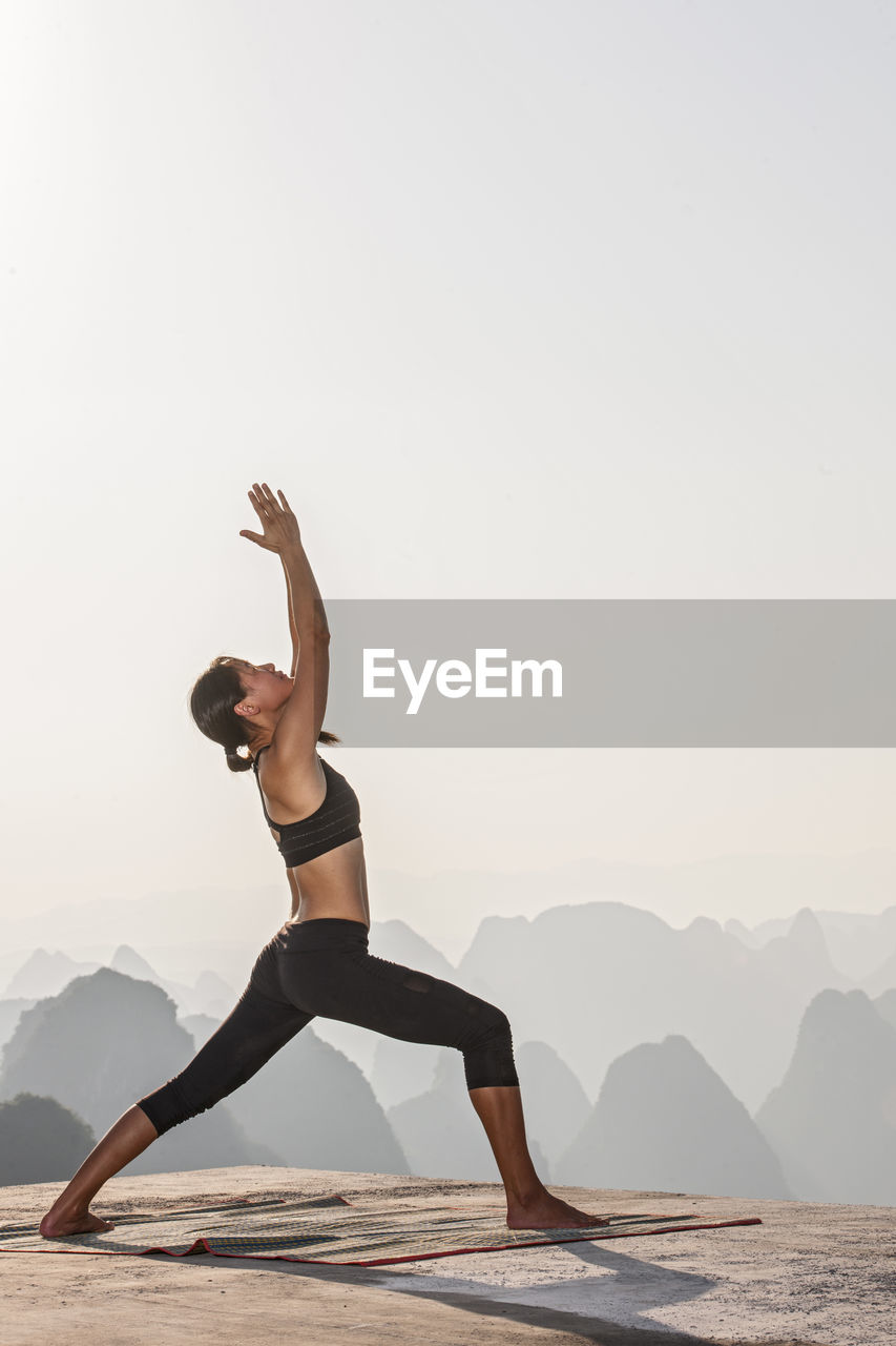 Beautiful woman practising yoga above the kast mountains of yangshuo