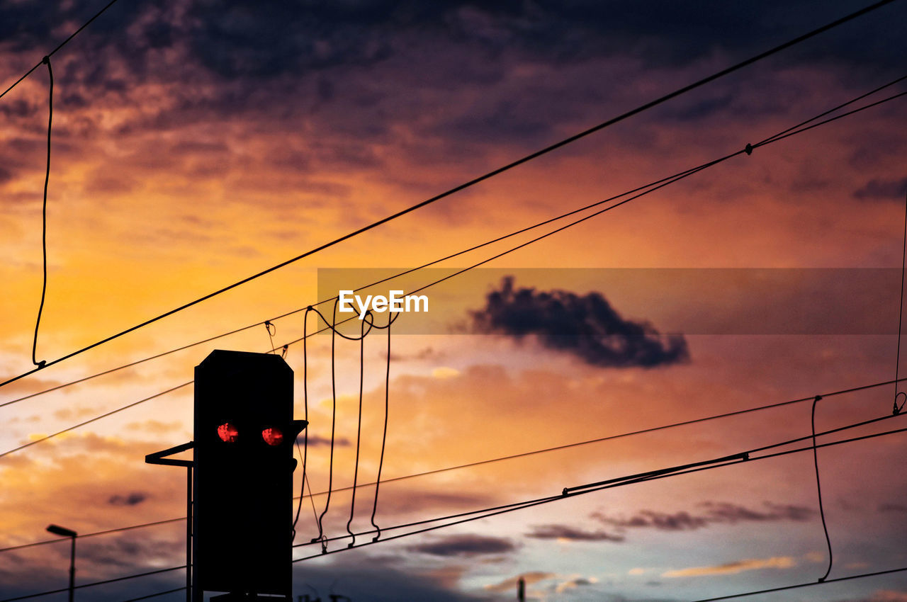 Low angle view of silhouette electricity pylon against sky during sunset