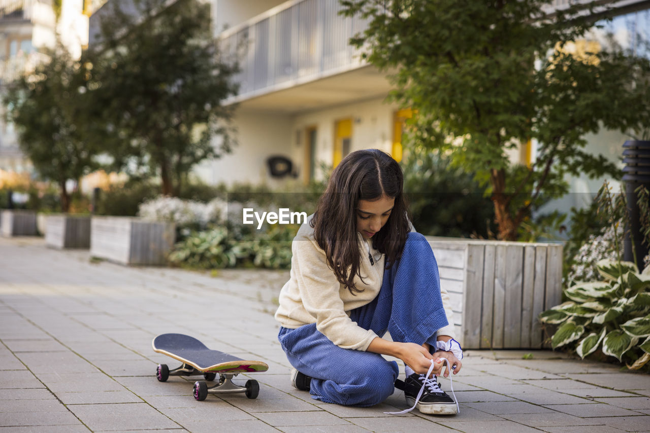 Girl skateboarder tying shoes