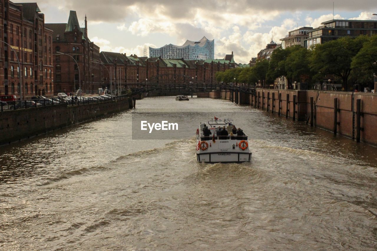 BOAT IN RIVER AGAINST SKY IN CITY