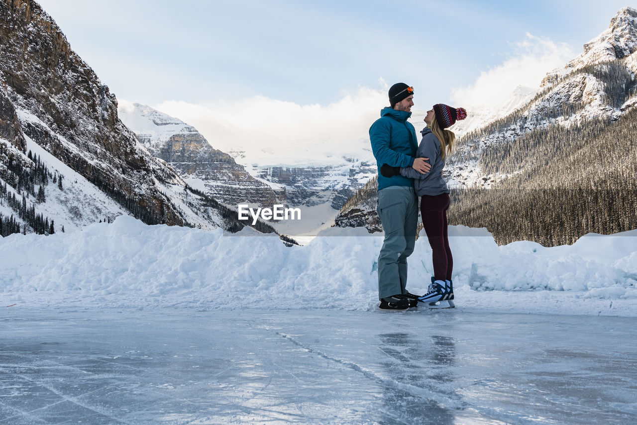 Young couple skating together on frozen lake louise in winter