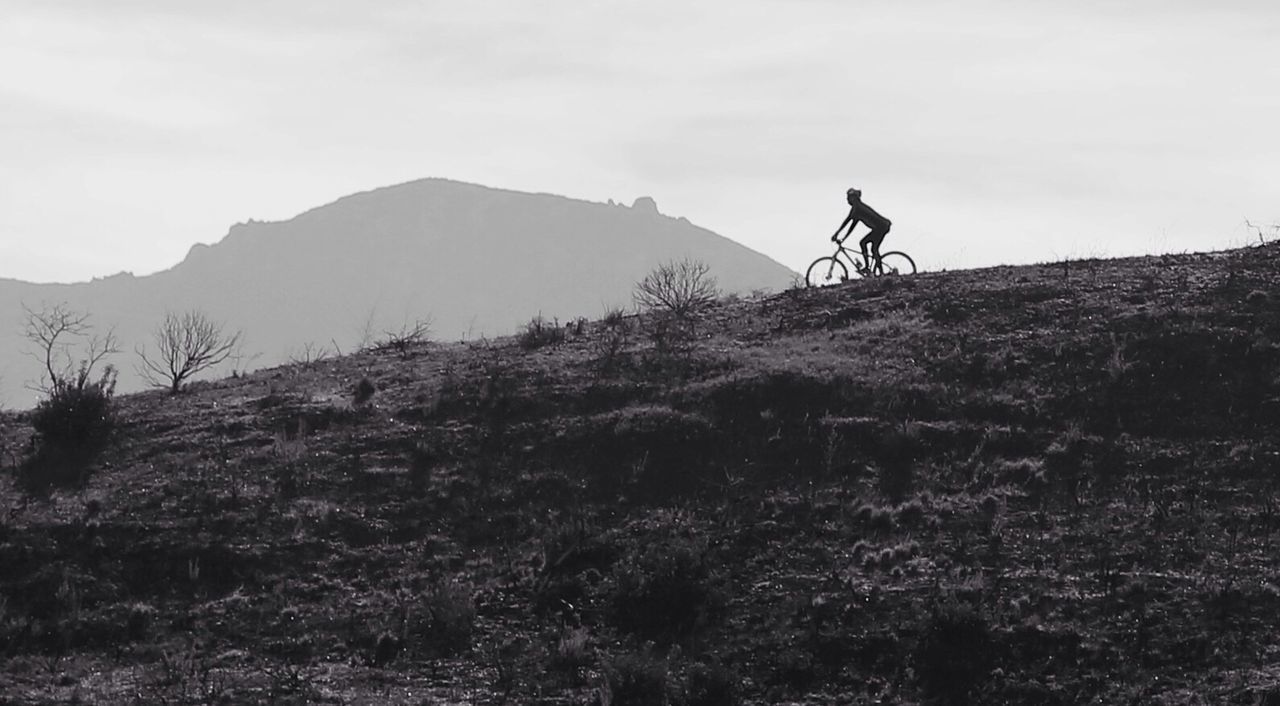Silhouette person riding bicycle on mountain