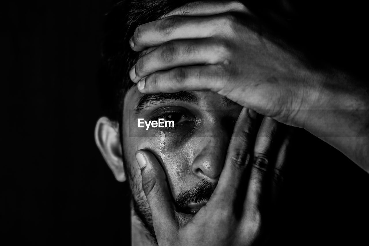 Close-up portrait of man making face over black background