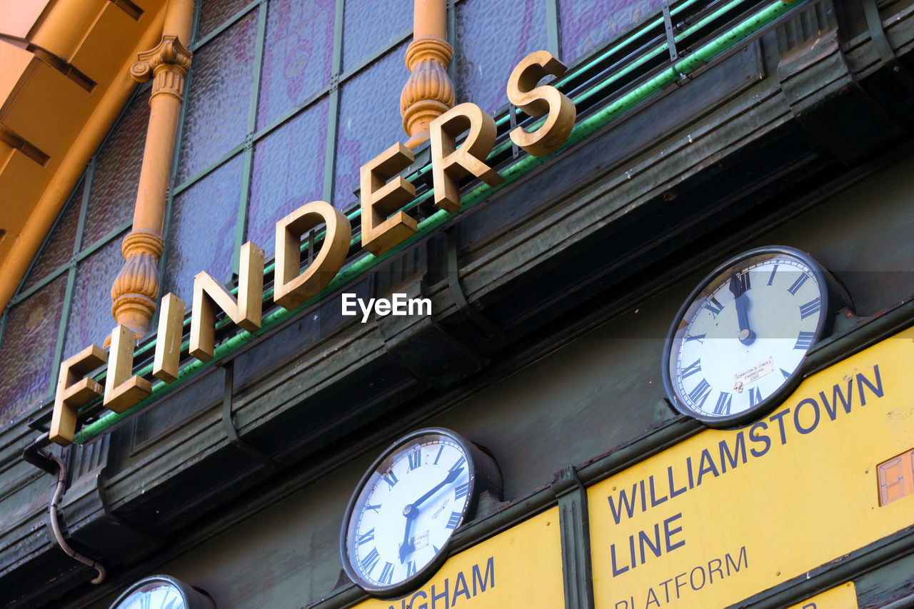 Low angle view of clocks and signs on wall at flinders street railway station