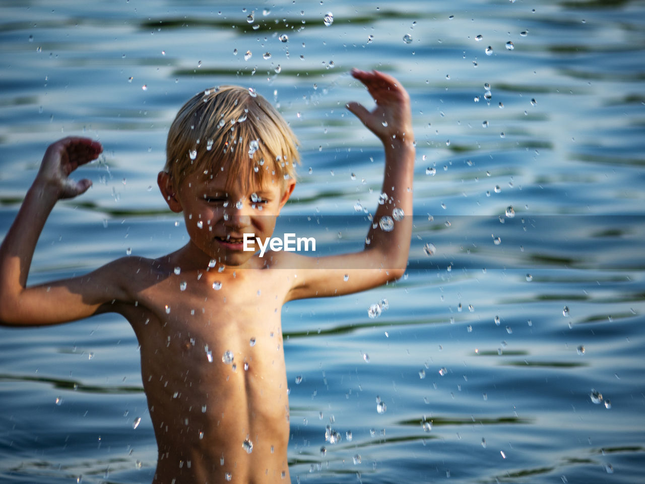 Shirtless boy standing in lake