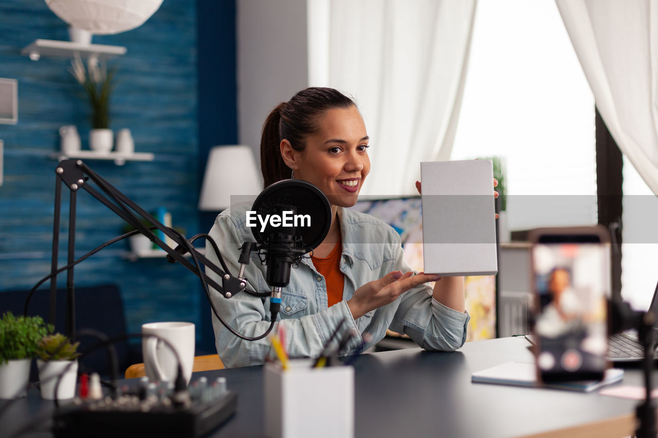 Woman wearing headphones doing podcast in office