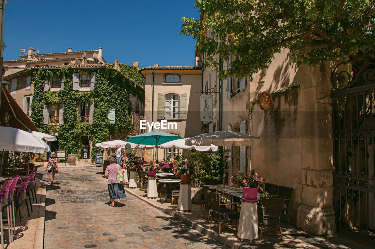 PEOPLE WALKING ON STREET AGAINST BUILDINGS