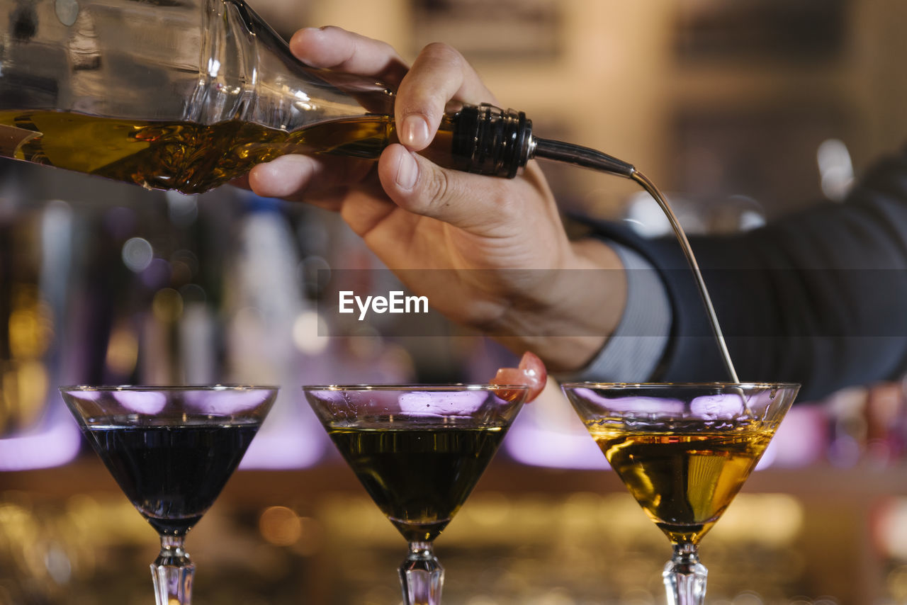 Cropped hands of male bartender preparing cocktail at bar counter