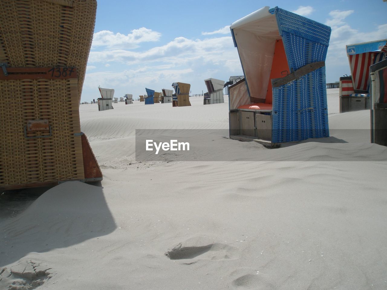 Hooded chairs at beach on sunny day