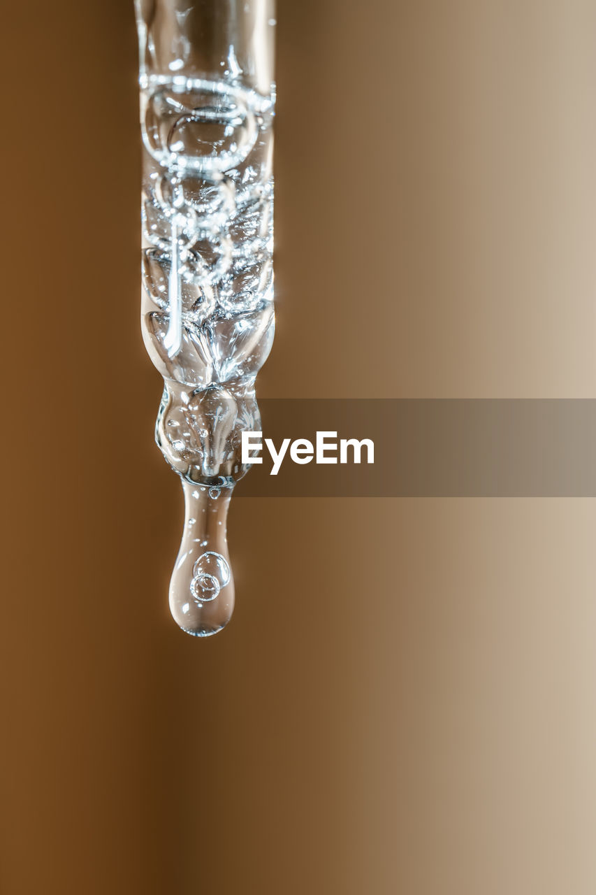 A drop of cosmetic oil falls from the pipette