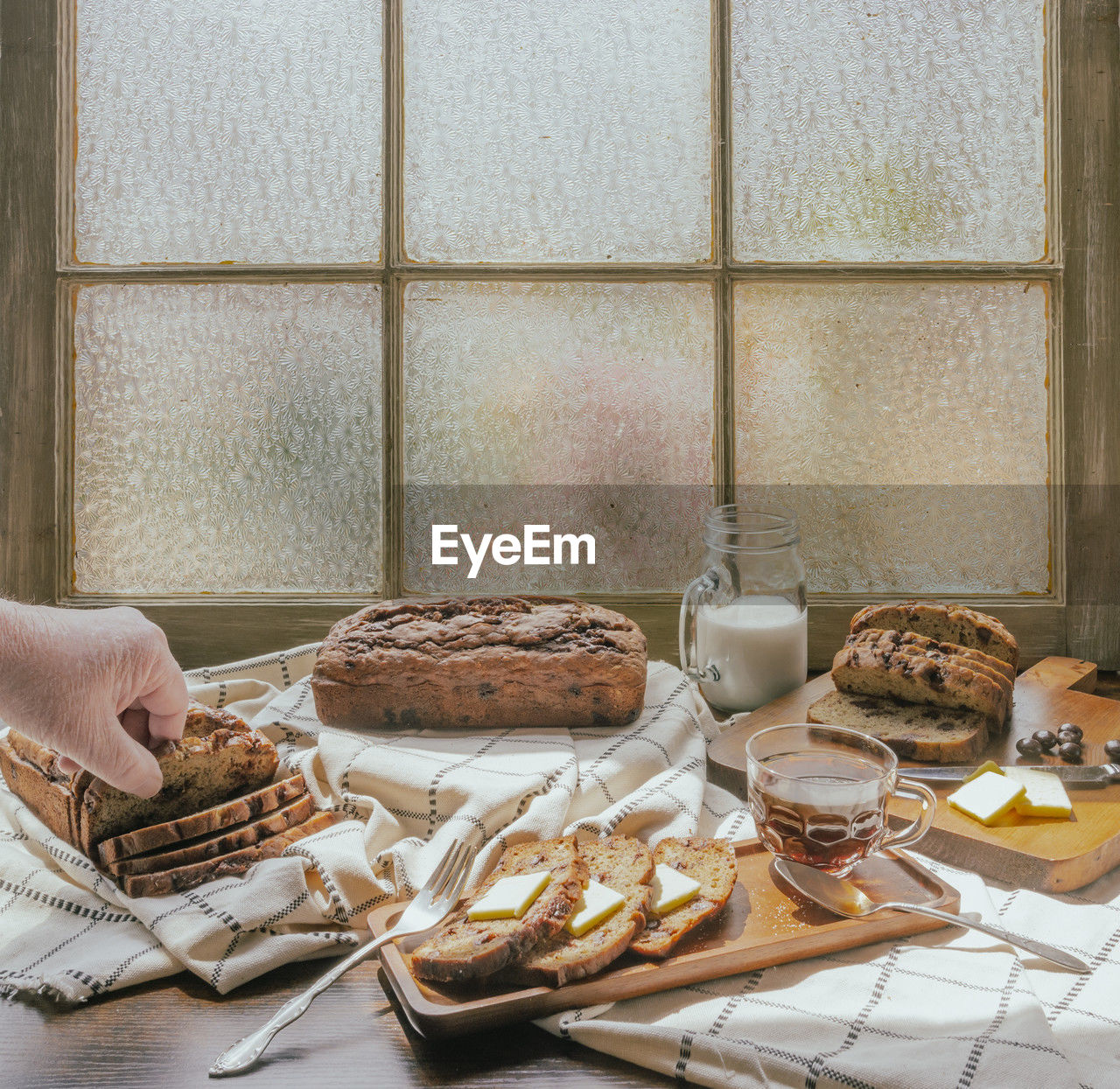 High-angle view of human hand reaching for banana bread