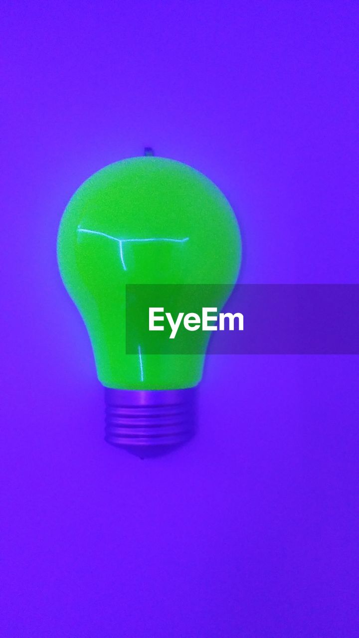 Close-up of light bulb against purple background