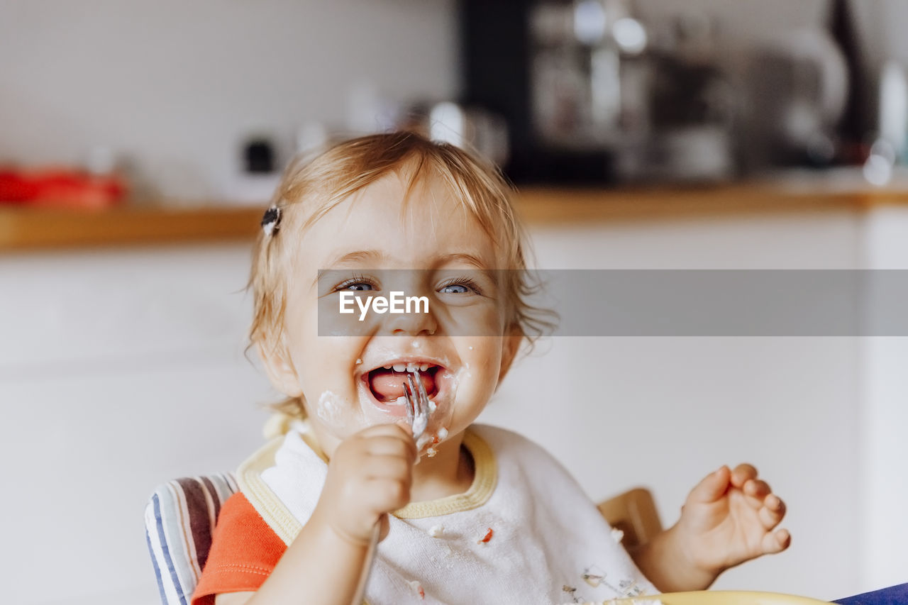 Smiling cute girl eating food at home