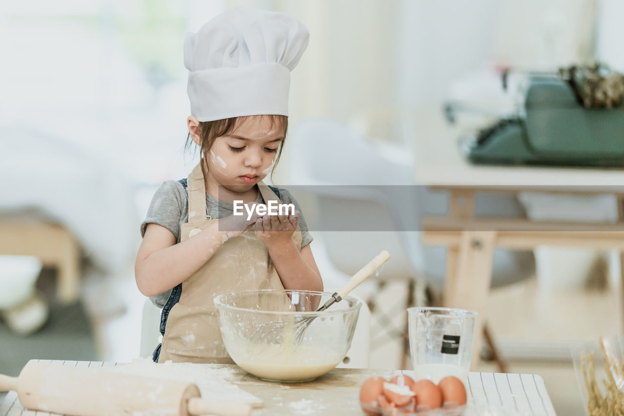 GIRL HOLDING ICE CREAM ON TABLE AT HOME