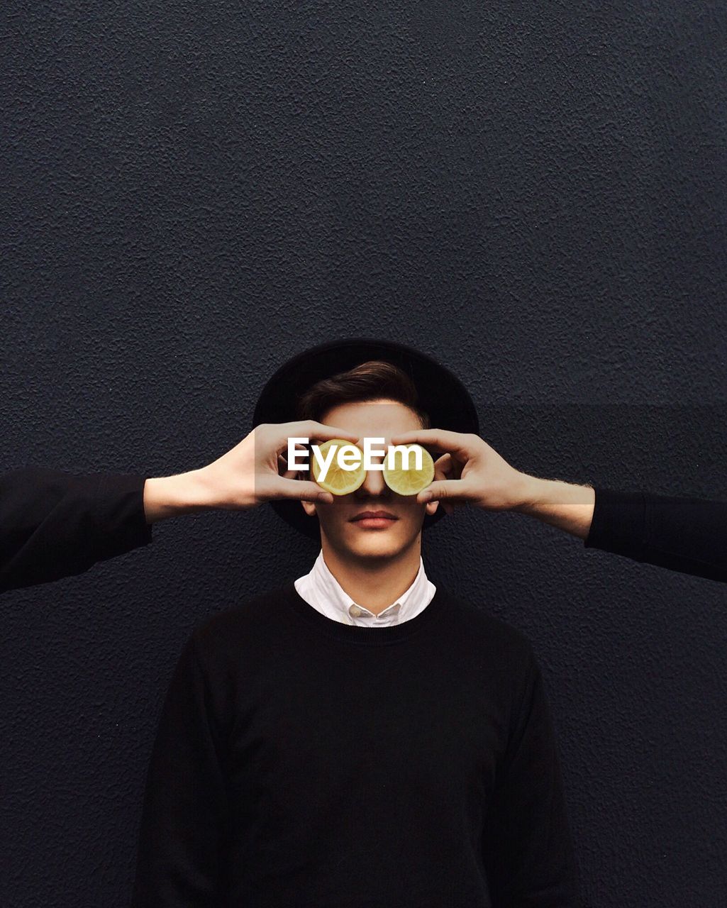 Cropped image of friends covering mans eye with lemon slices