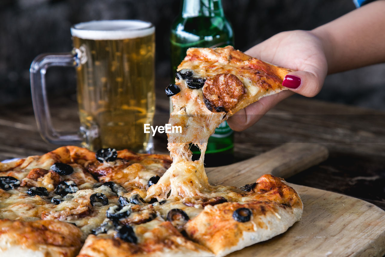 Close-up of hand holding pizza slice on table