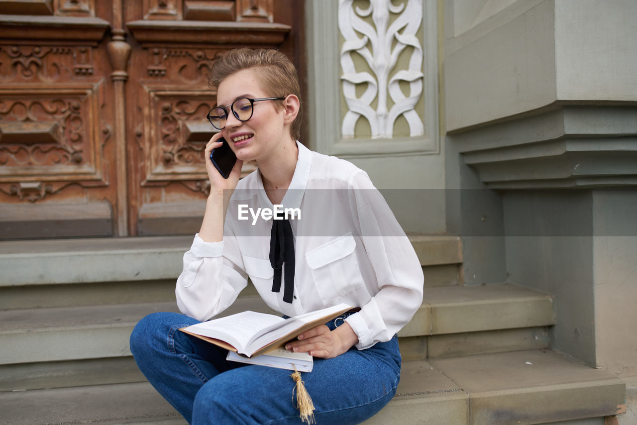 Full length of teenage girl sitting on book