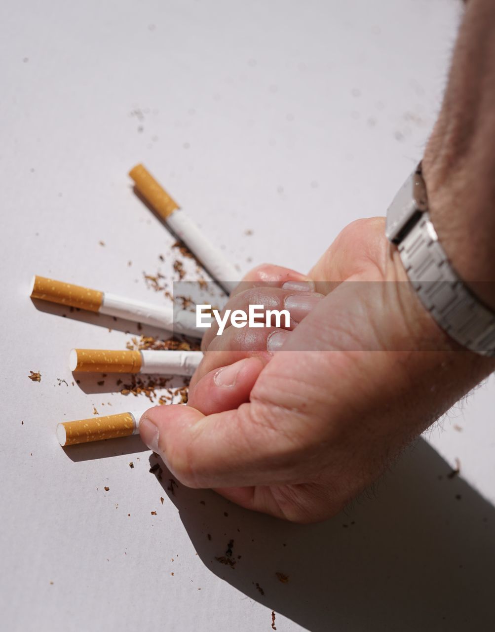 Close-up of hand crushing cigarettes