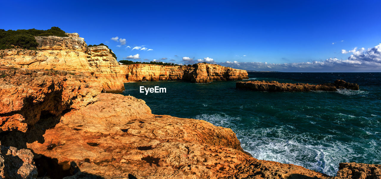 SCENIC VIEW OF SEA AND ROCKS AGAINST BLUE SKY